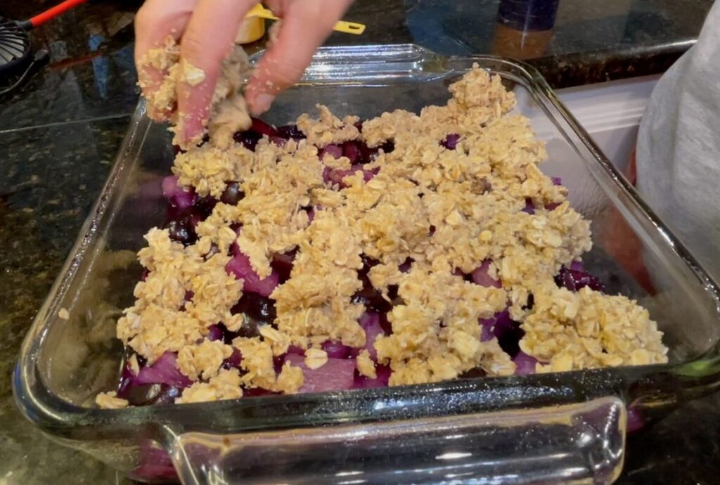 A mouthwatering image of a pan filled with a gluten-free cherry crisp. The crisp has a golden brown, bubbly topping and is filled with glistening red cherries.