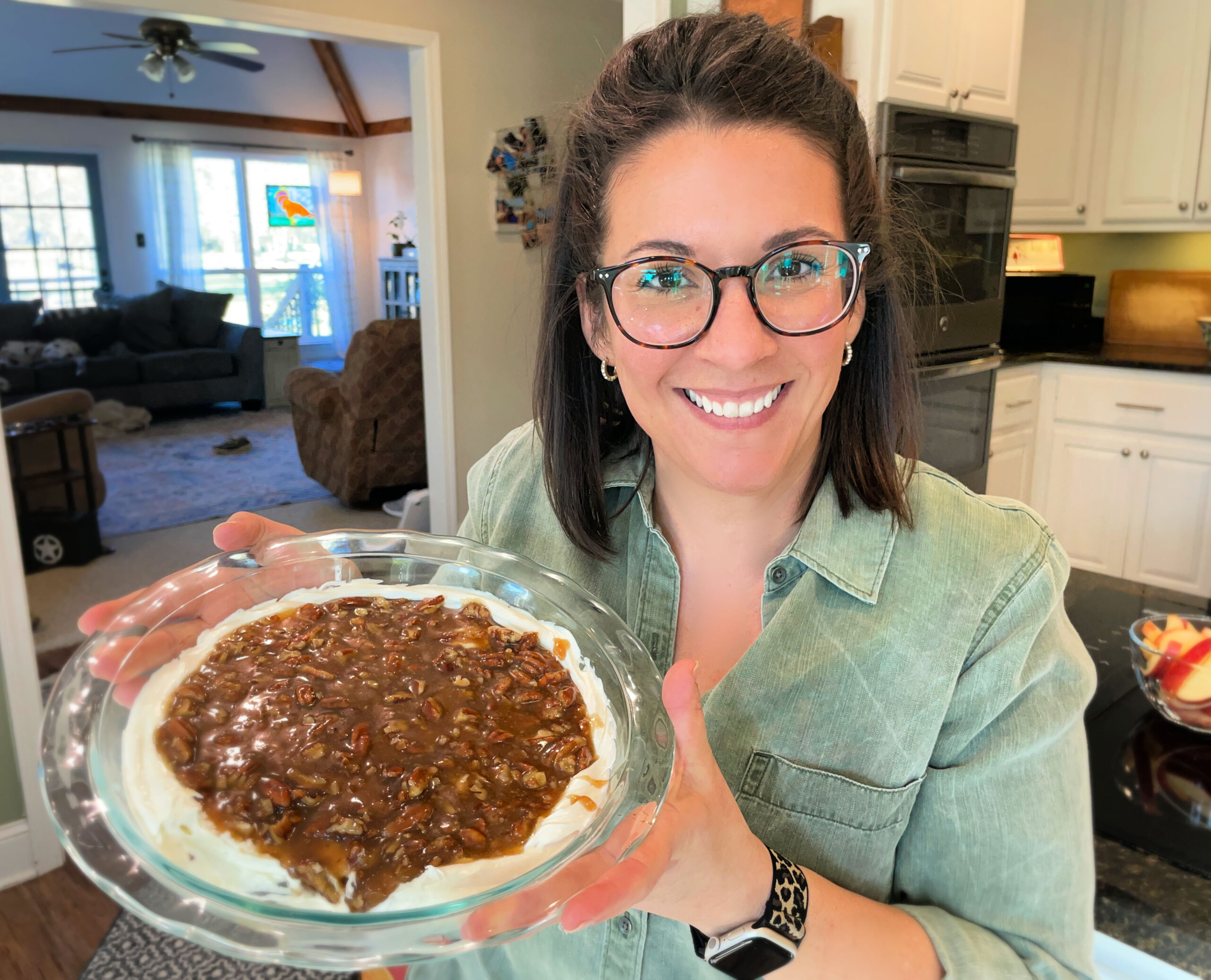 Sara Brown of Brown Family Foods stands in her kitchen holding a pan of pecan pie dip smiling.