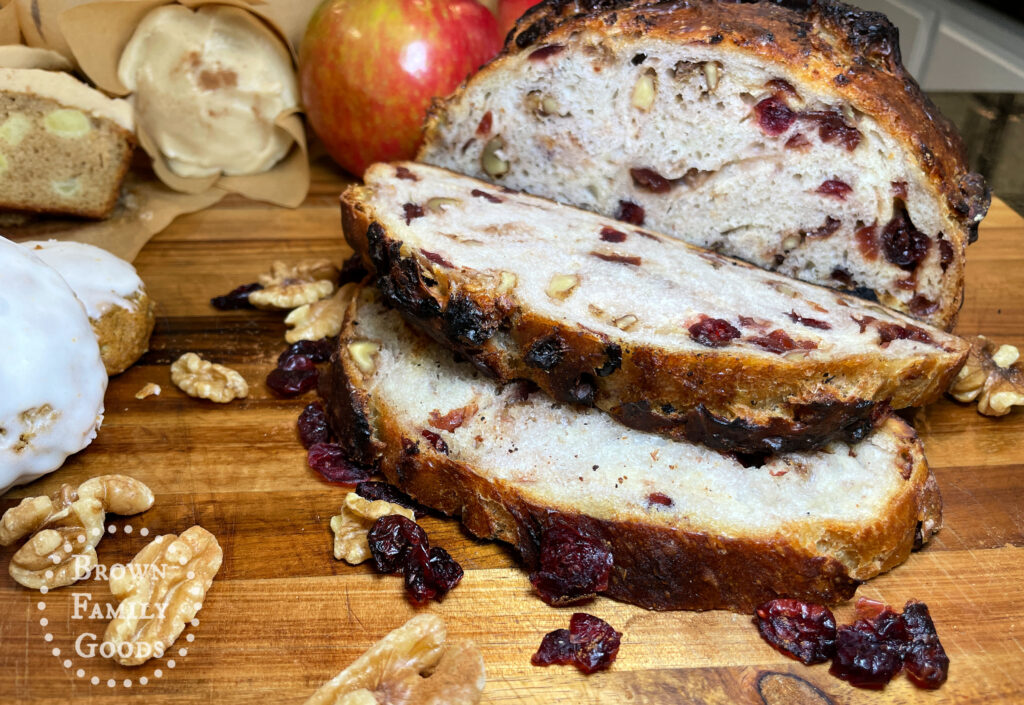 Slices of No-Knead Cranberry Walnut Bread showing dried cranberries and chopped walnuts on a wooden board.