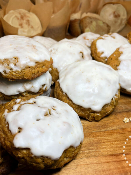 Pumpkin Oat Brown Butter Cookies with White Glaze Stacked on a Wooden Board